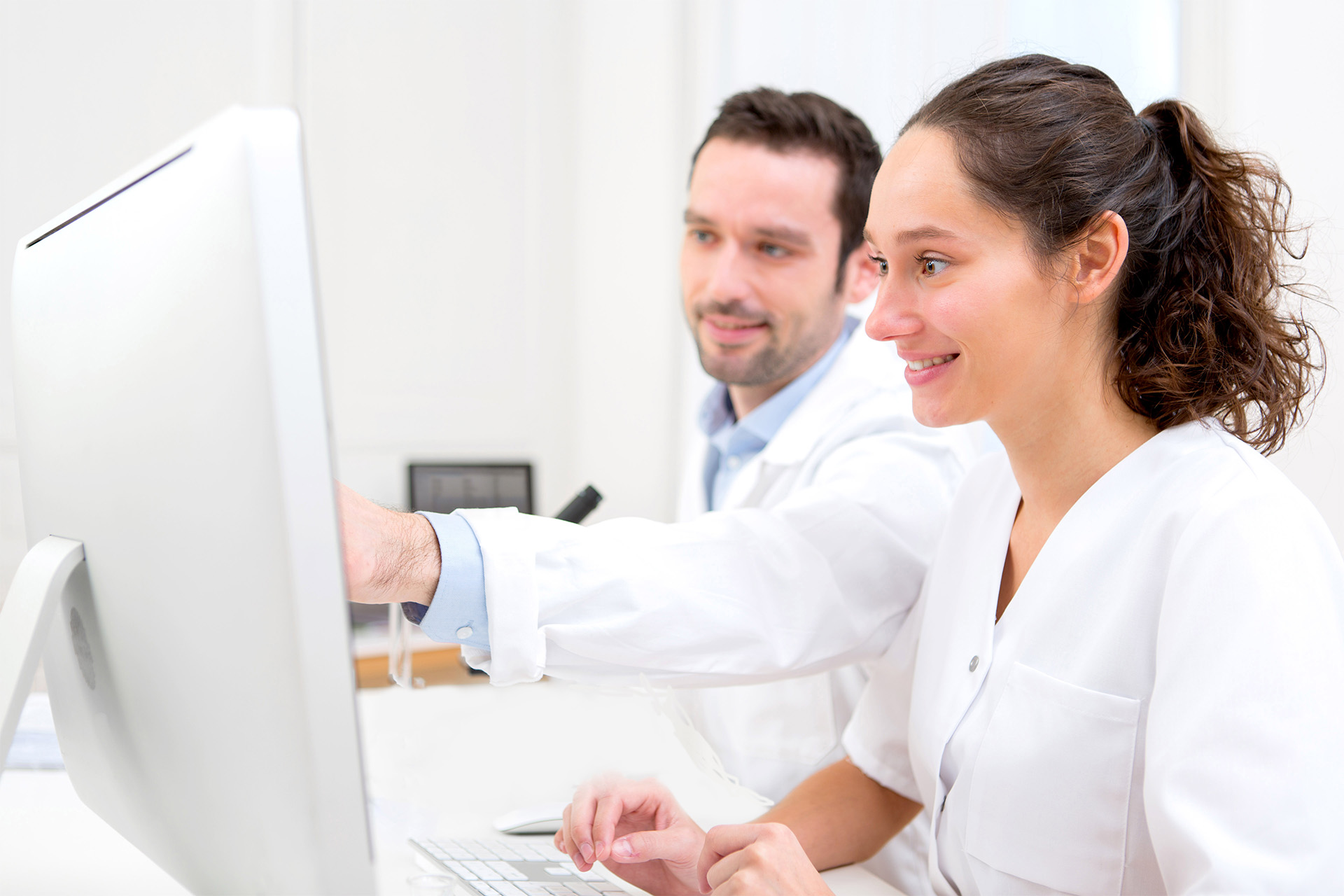 Two pharmacy professionals focused on a computer monitor to learn virtually.
