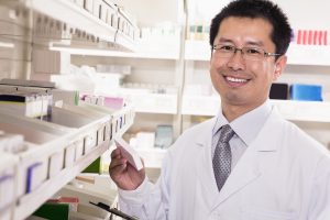 Male pharmacist selects a drug from a dispensary shelf