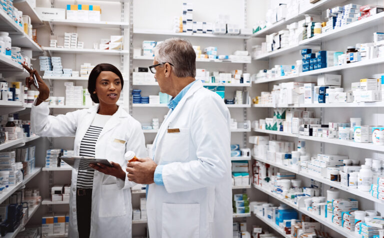 Two pharmacy professionals discuss a medication in the dispensary.