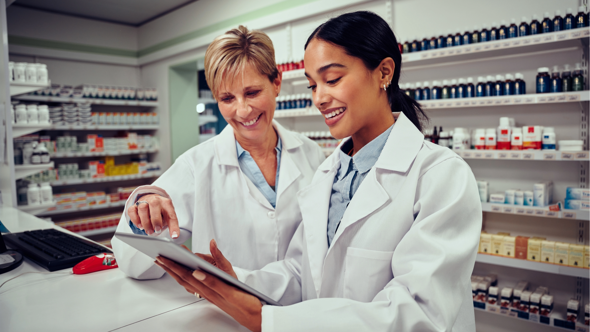 Two pharmacy professionals enter a safety self-assessment into a tablet device.